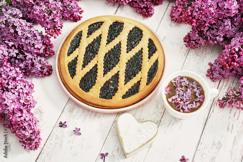 Closeup - tasty homemade tart and lilac flowers.Cake and cup of tea or coffee. Romantic breakfast. Happy Birthday Card. Hello spring and summer.Greeting card for Women's Day and Mother's Day.
