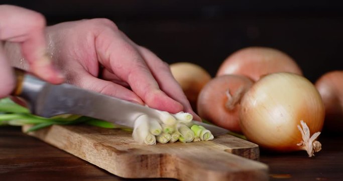 Hands men crushed green onion on wooden cutting Board.