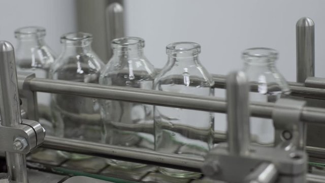 glass bottles on medical solution conveyor line close up medical industry