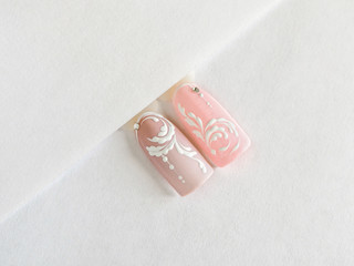 Delicate pink summer manicure with monograms. Tips with a monogram pattern on a white background