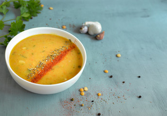Pea soup in a white bowl. Pea cream soup in a plate on a blue background. Healthy vegan food. Free space for text