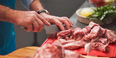 The chef cuts a meat with a knife.