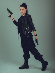 Naklejka premium Shot of a sexy military woman posing with guns,in a black jacket