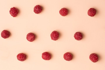 several neat red fresh raspberries on a pink surface.