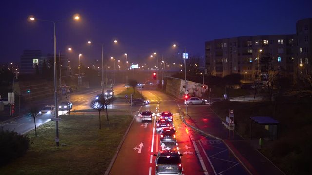 Cars wait at a red traffic light on a road in a city in the evening - top view