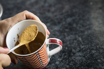 a girl making hand beaten coffee or indian cappuccino in a mug with a spoon