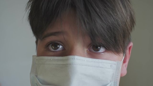 close-up baby's eyes full of tears the rest of his face is covered with a medical mask