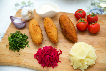 Ukrainian tradition food on a wooden board . Red cabbage sauerkraut in a small bowl . mashed potatoes . Mayonnaise, Garlic, Onion, Tomatoes. Chopped coriander.Chicken Kiev cutlets with parsley leaves.
