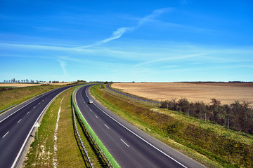 Agricultural landscape and bend of a two-lane asphalt expressway in Poland.