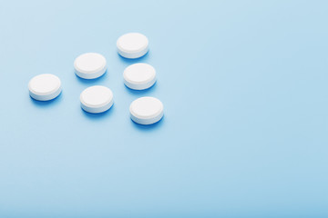 White medicinal tablets in the shape of a pyramid on a blue background.