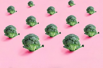 Broccoli on a pink background. Seamless minimalistic isometric pattern, photo collage, vegan pop art design, vegetable backdrop. Postcard, print on fabric, wrapping paper.