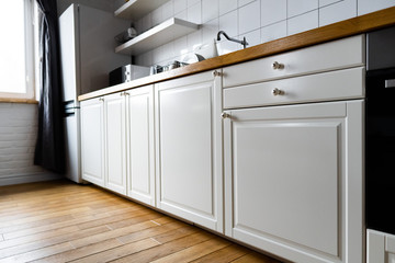 Appliances and furniture: bright white cabinets with wooden countertop, electric cooker, induction...