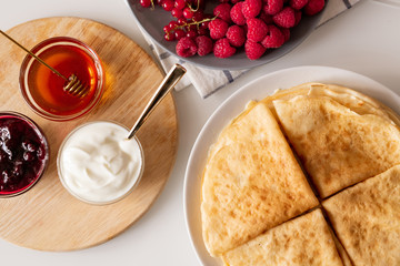 Pancakes, fresh raspberries and red currant, honey, cherry jam and sourcream