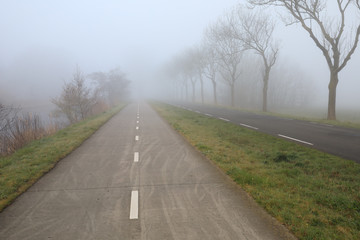 Fototapeta na wymiar cycling path in countryside in dense fog