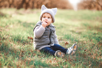 a boy in a gray warm vest and a gray cap plays games in the open air against the background