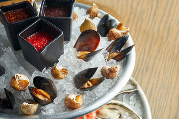 Close up view on tasty plate with seafood on ice - mussels and raps. Healthy Antipasti. Wooden background. Selective focus