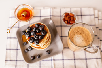 Top view of appetizing homemade pancakes and glass of aromatic cappuccino