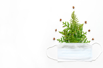 composition of thuja twigs in the form of a Christmas tree, and a medical mask isolated on a white background. The concept of the new year during the corona virus covid-19. space for text
