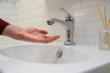 Man holding his hand under opened tap without water. Shutdown of water supply for non-payment or...