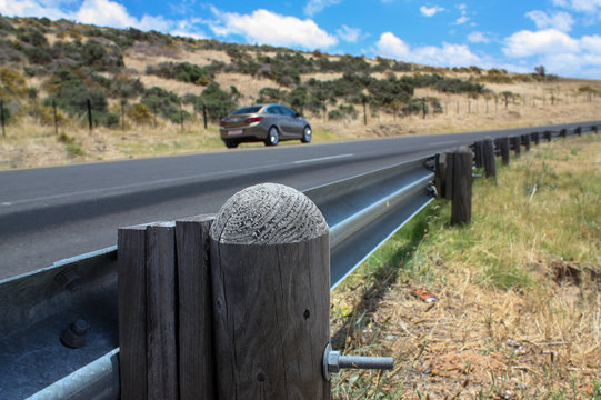 Roadside barrier with car parked in the background