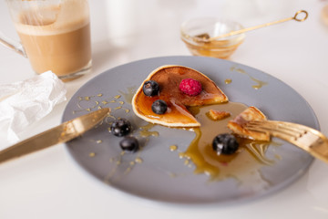 Small homemade pancake with honey, raspberries and blackberries on plate