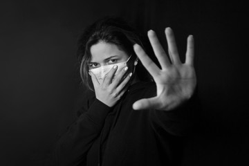 black and white stop the virus and epidemic diseases. Healthy woman in blue medical protective mask showing gesture stop.