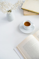 books, coffee mug glasses and pink rose on the table on a white background