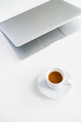 coffee mug and gray laptop on the table on a white background