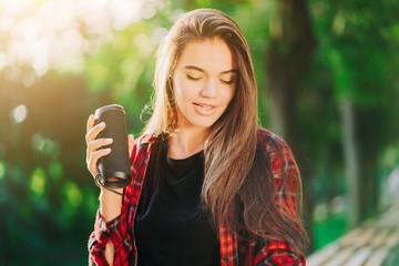 Modern trendy girl listening to music by wireless portable speaker.Young beautiful american woman enjoying,dancing in park.