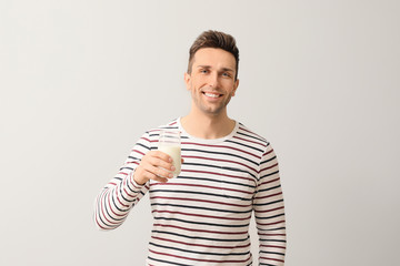 Young man with glass of milk on grey background