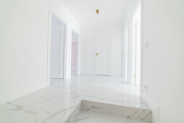 Fototapeta na wymiar White empty corridor with white doors and gold fittings and ceiling lights. Home design
