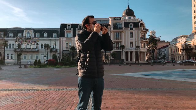 Tourist Man Wearing Face Medical Mask Takes a Pictures on the Street. Prevention of infection Coronavirus or Covid 19 in the air. Air Pollution Protection