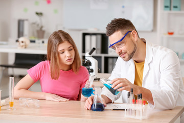 Fototapeta premium Teacher and pupil at chemistry lesson in classroom