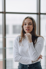 attractive girl on the background of the window shows different emotions and mood. girl on a light background indoors.