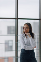 attractive girl on the background of the window shows different emotions and mood. girl on a light background indoors.