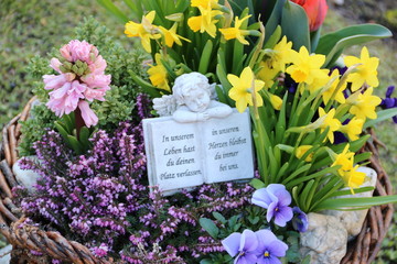 Grabschmuck mit Engel und Text zwischen Blumen auf dem Friedhof 