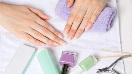 Obraz na płótnie Canvas Manicure. Women's hands on a towel. Manicure tools, nail Polish. Home nail care, SPA, beauty. Long natural nails. Beauty salon.