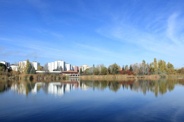 Fototapeta na wymiar Paisaje con lago y edificios al fondo. Azul.
