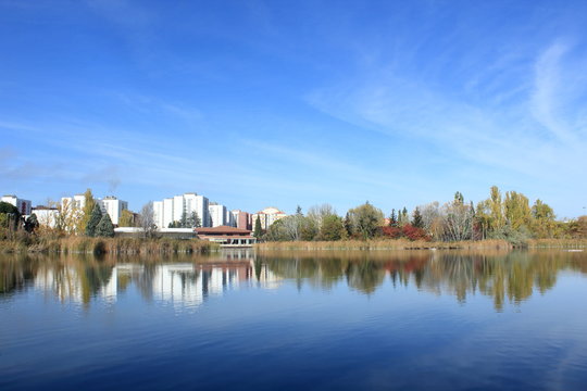 Paisaje con lago y edificios al fondo. Azul.