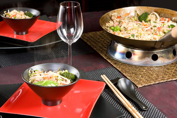 Asian stir fry dish with chop sticks and black and red plates