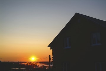wooden rural house on the background of the sunset, Russia