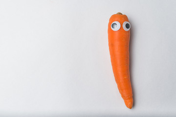 Carrot with funny face and Googly eyes on white background. Vegetarianism concept