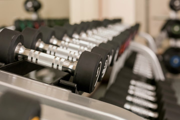 Naklejka premium Dumbbells on stand in modern gym