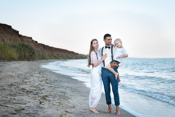 Beautiful couple with small child on sea background. Young parents, happy parenthood
