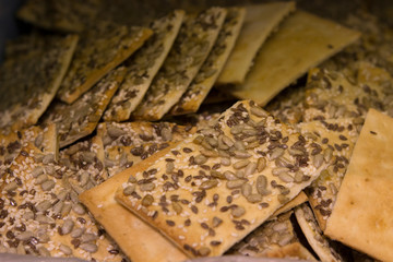 thin salty cookies with sunflower and sesame seeds on the counter of the bakery department of the store