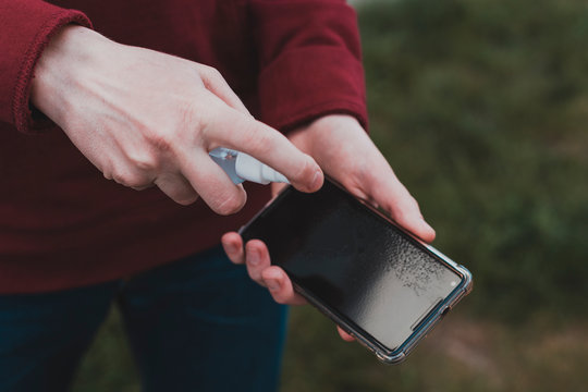 Cleaning mobile phone screen with disinfecting wet wipes for clean smartphone preventive wiping for COVID-19 Coronavirus outbreak contamination prevention.