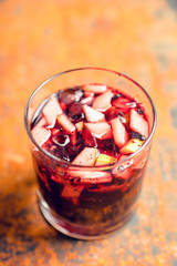 Old fashioned cocktail with blackberry liqueur and apple slices on rustic background. Selective focus. Shallow depth of field.