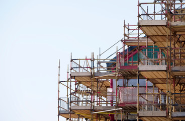 Scaffold and red net surrounding house renovation for safe access to refurbishment height