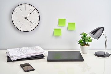 Workspace, desktop at home with laptop, phone, supplies and sticky notes on the wall. Business and home office concepts. White background with copy space for text.