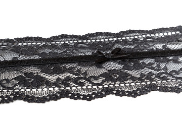 Close-up of black see-through lace ribbon with a small bowtie, isolated on white background.